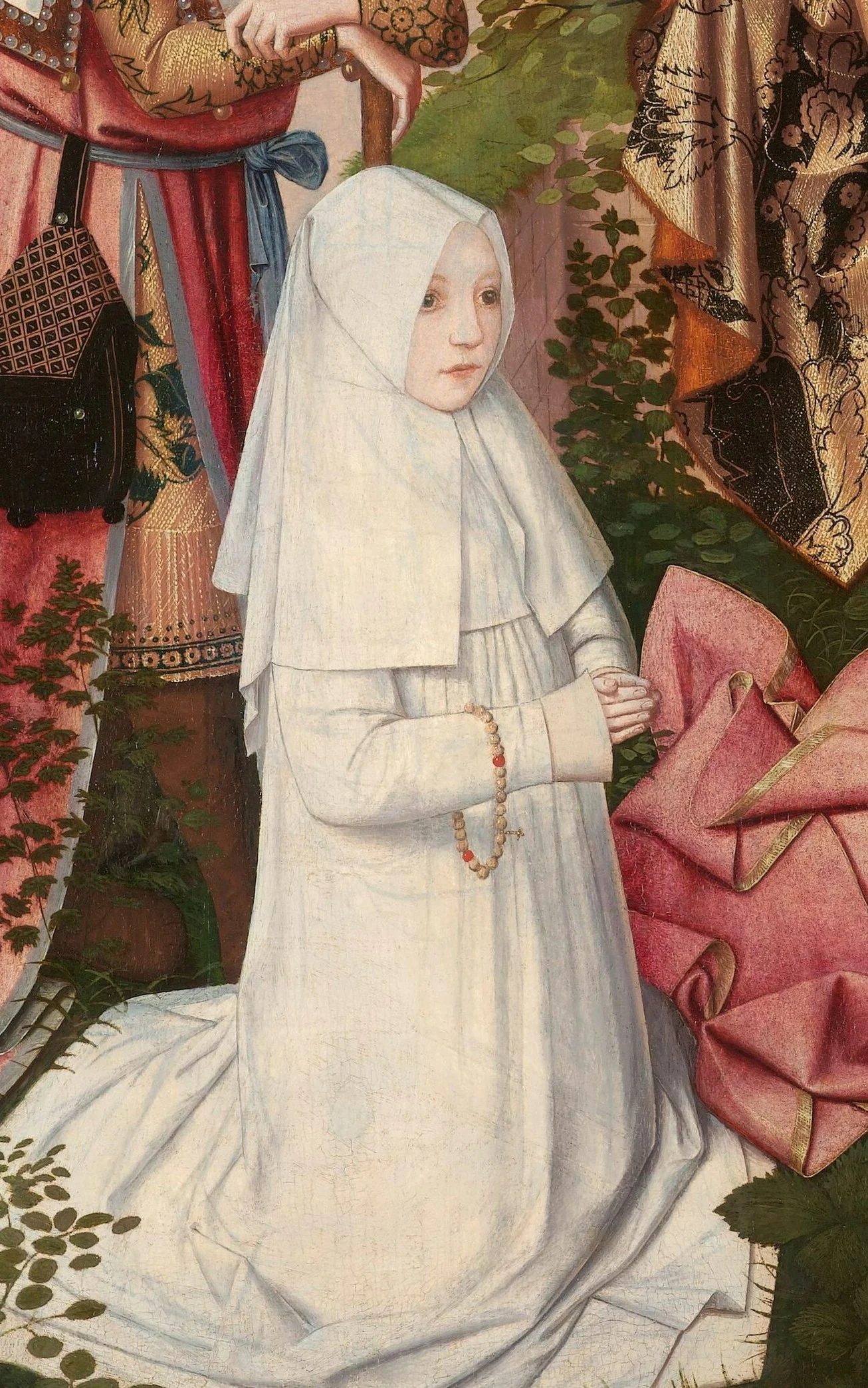A nun in a white habit kneels at the foot of the tree.