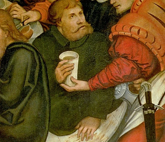 Luther turns round on his seat and takes the cup from the servant.