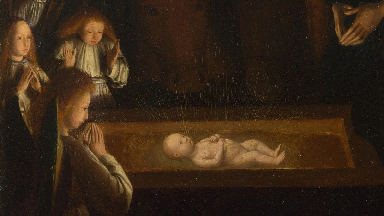 Small angels kneel at the manger; their faces are lit from below.