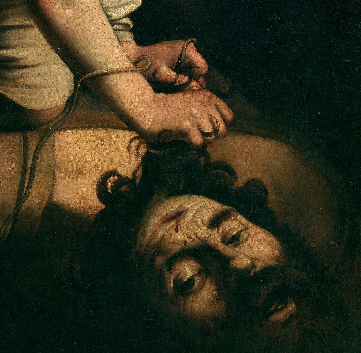 David's hands are busy with the cord. Below them lies the huge head, the wound of the stone on its forehead.