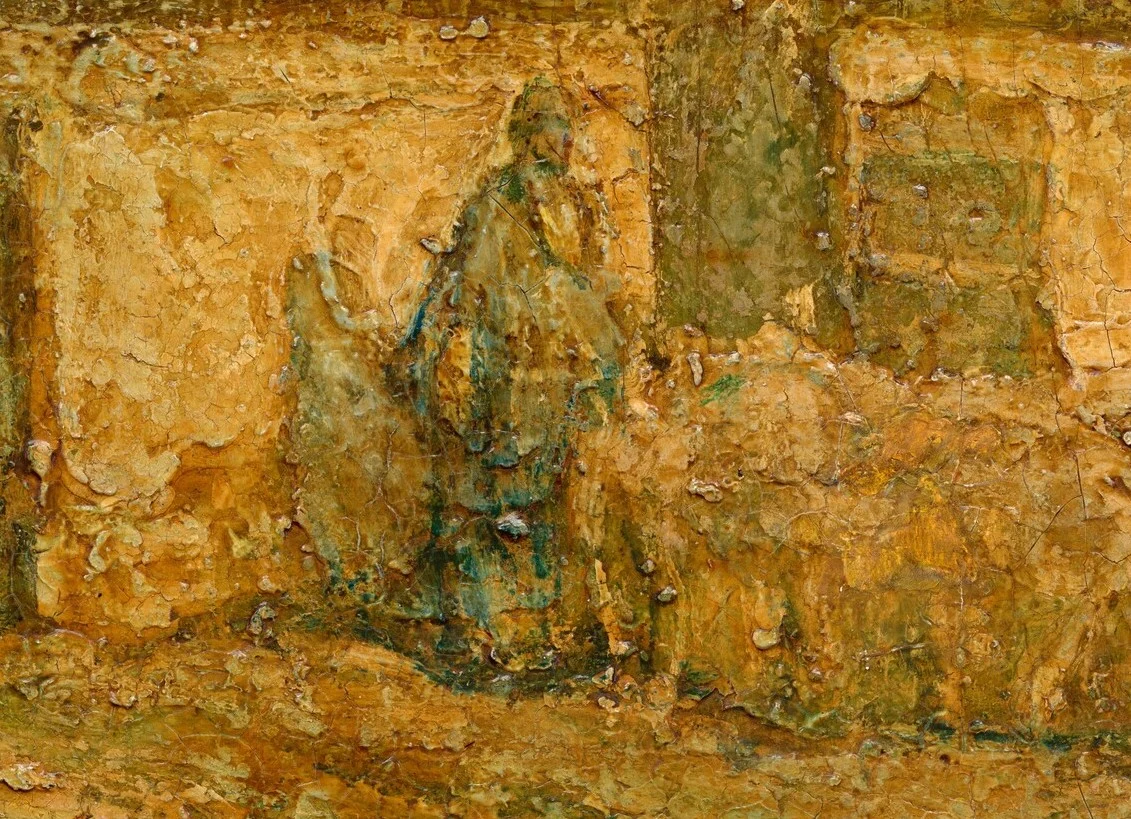 The shepherd stands in front of the house, the sheep pressed close around him.