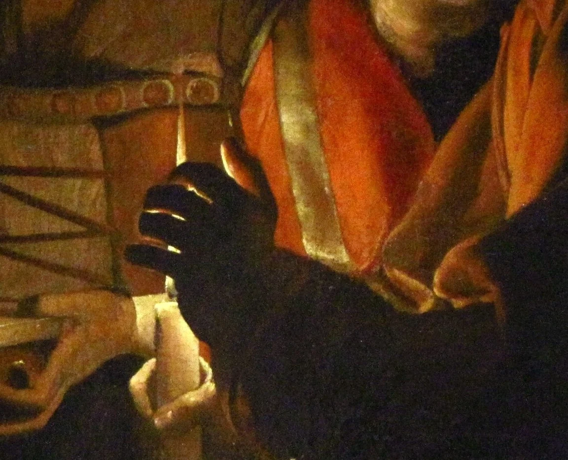 Joseph's hand hides the flame. We see only what it lights.